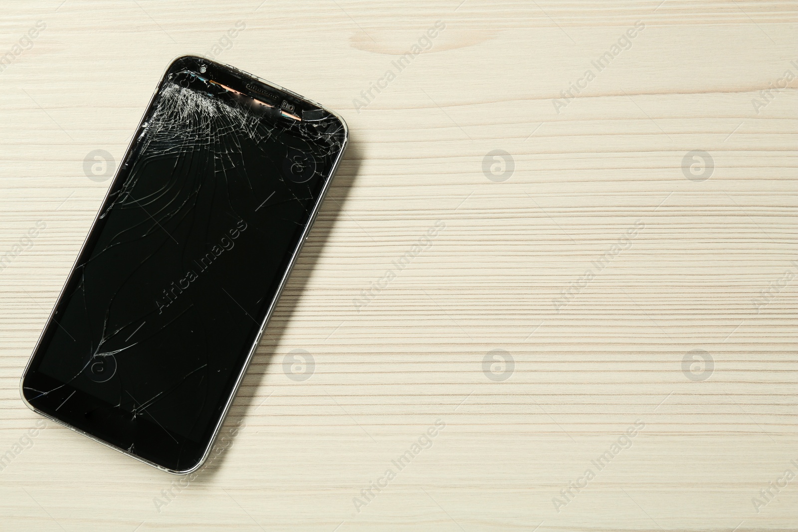 Photo of Damaged smartphone on wooden table, top view with space for text. Device repairing