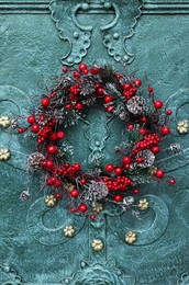 Photo of Beautiful Christmas wreath hanging on turquoise metal door