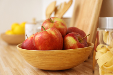 Photo of Apples in bowl on wooden countertop in kitchen. Interior element