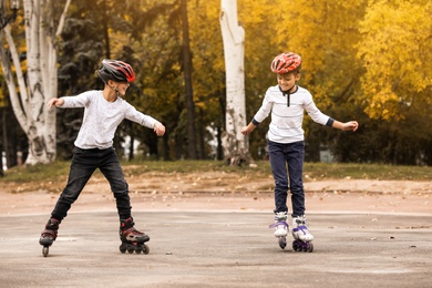 Happy children roller skating in autumn park