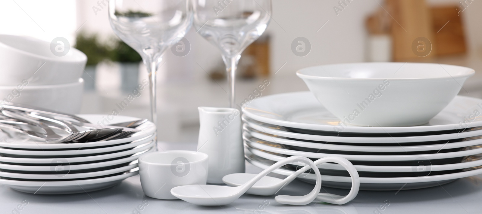 Photo of Set of clean dishware, glasses and cutlery on table in kitchen