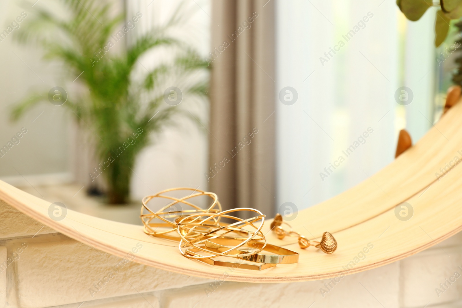 Photo of Round mirror with female accessories on brick wall indoors, closeup. Interior design