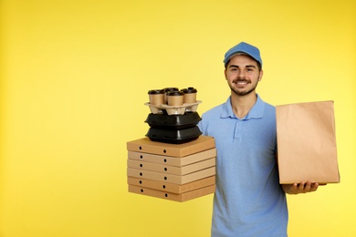 Young courier with different orders on color background, space for text. Food delivery service