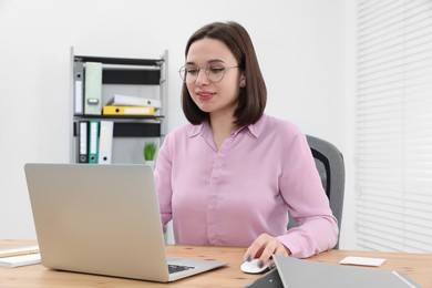 Photo of Young intern working with laptop at table in modern office