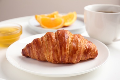 Delicious breakfast with croissant and honey on white table, closeup