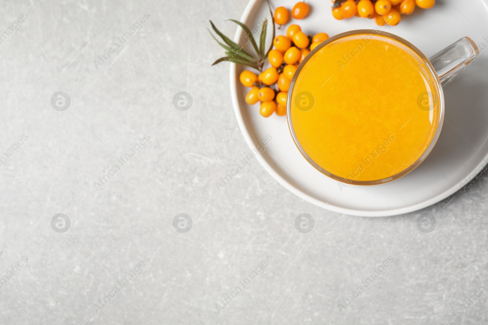 Photo of Delicious sea buckthorn tea and fresh berries on light grey table, top view. Space for text