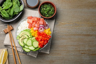 Delicious poke bowl with salmon and vegetables served on wooden table, flat lay. Space for text