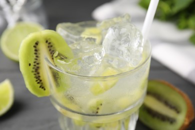 Photo of Glass of refreshing drink and cut kiwi on gray table, closeup