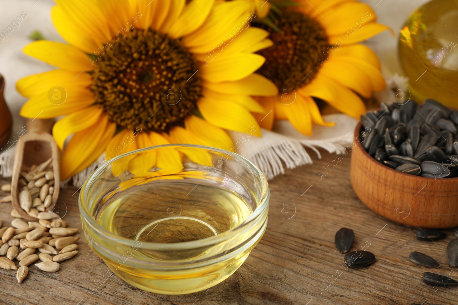 Photo of Sunflower oil and seeds on wooden table, closeup