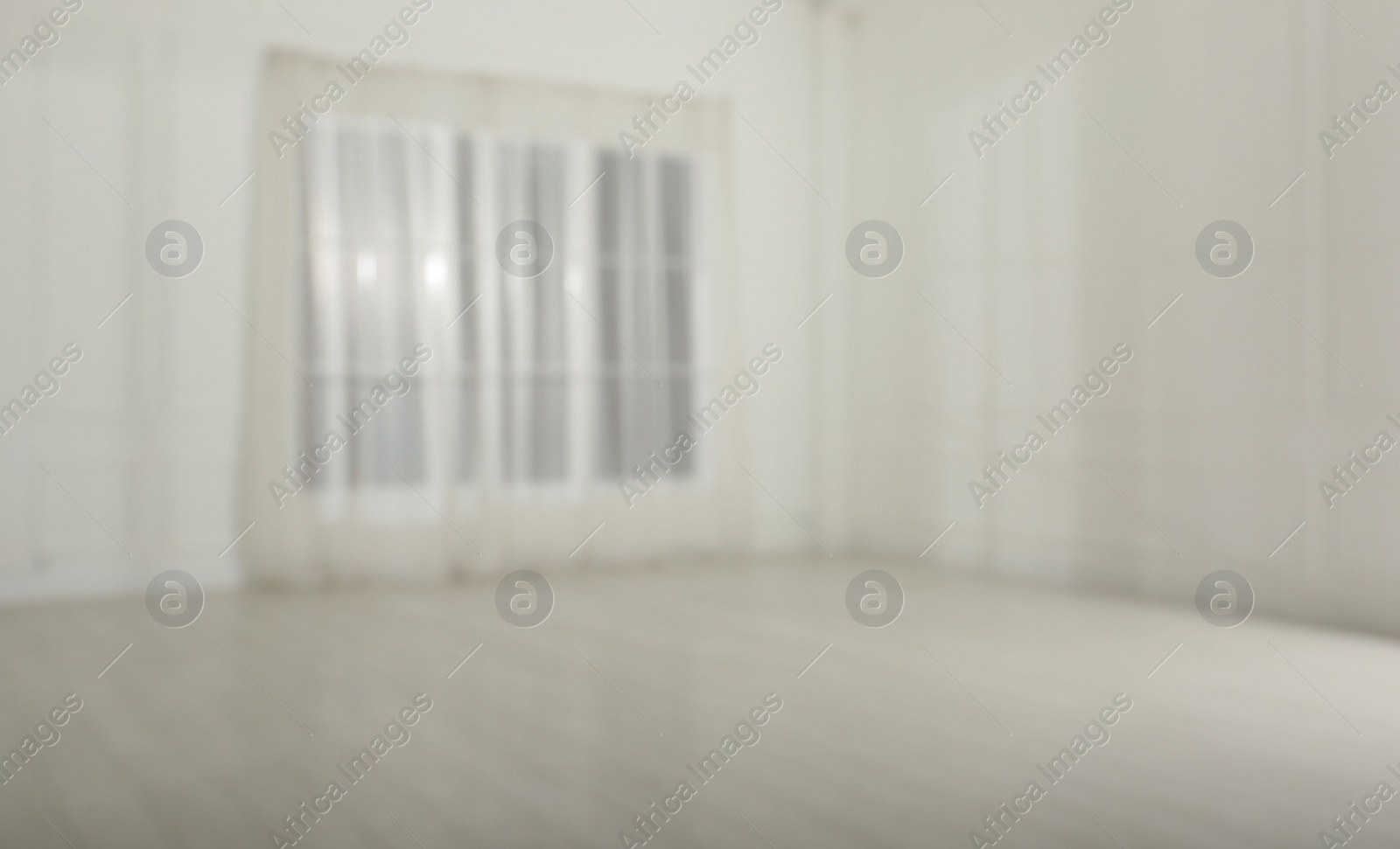 Photo of Empty room with white walls and large window, blurred view