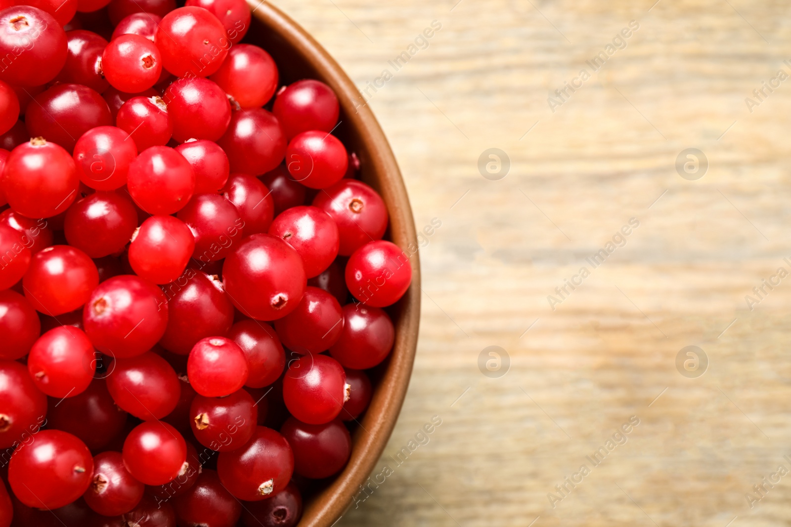 Photo of Tasty ripe cranberries on wooden table, top view. Space for text