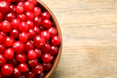 Photo of Tasty ripe cranberries on wooden table, top view. Space for text