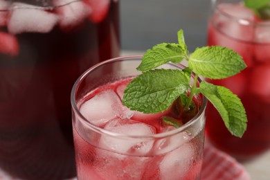 Photo of Delicious iced hibiscus tea with mint against blurred background, closeup