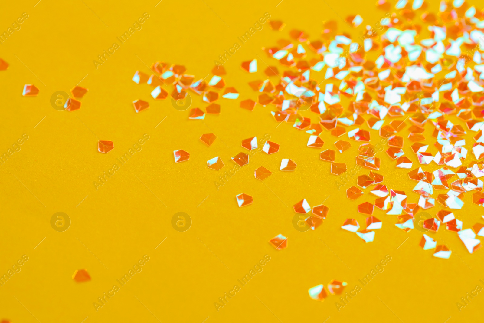 Photo of Pile of shiny glitter on orange background. Space for text