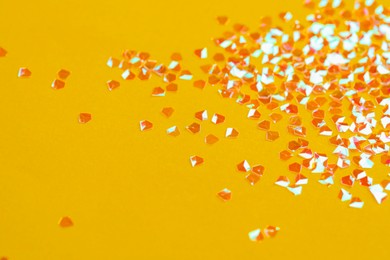 Photo of Pile of shiny glitter on orange background. Space for text