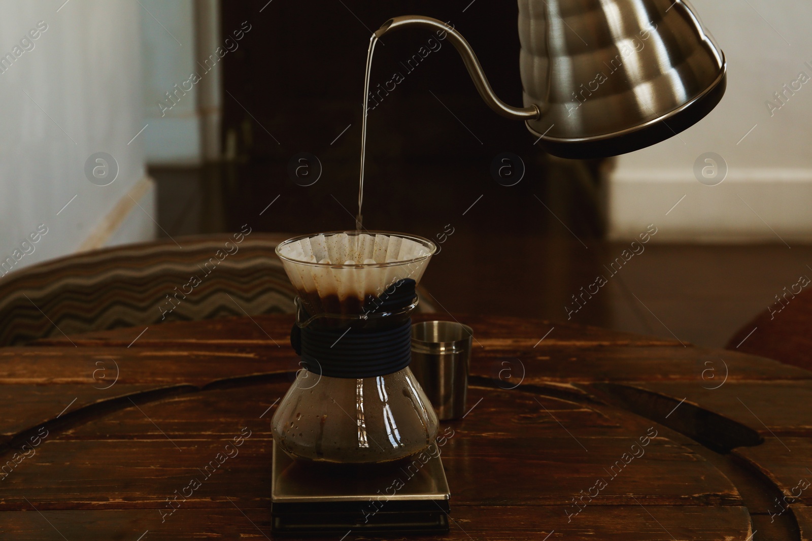 Photo of Pouring water from kettle into cup with coffee and wave dripper in cafe, closeup