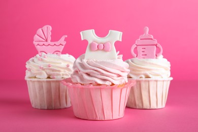 Beautifully decorated baby shower cupcakes for girl with cream and toppers on pink background