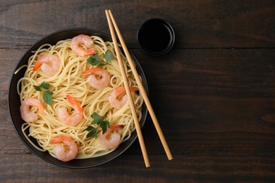 Tasty spaghetti with shrimps, parsley and soy sauce on wooden table, top view. Space for text