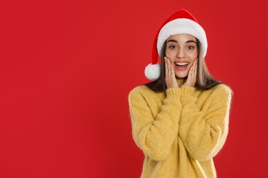 Photo of Excited woman in Santa hat on red background, space for text. Christmas countdown