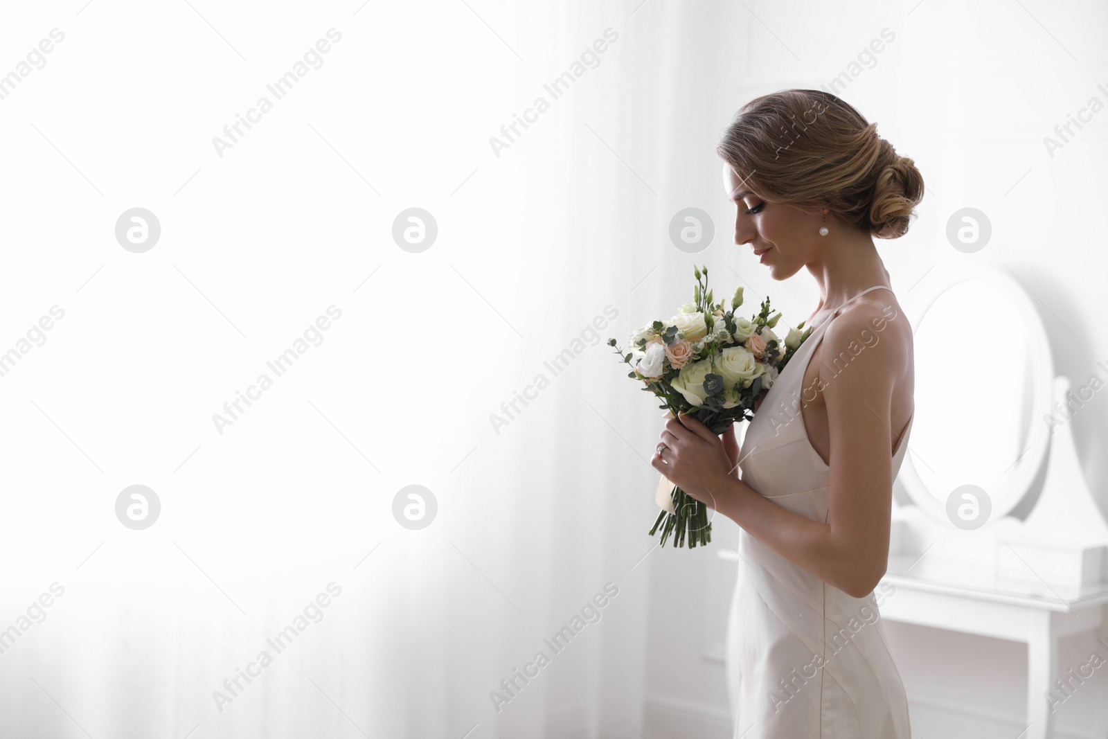 Photo of Bride in beautiful wedding dress with bouquet indoors. Space for text