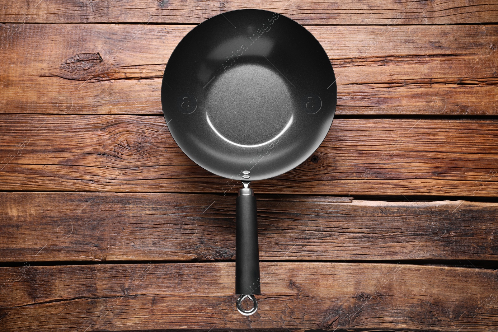 Photo of Empty iron wok on wooden table, top view. Chinese cookware