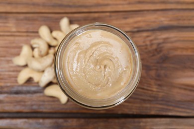 Tasty cashew nut paste in jar on wooden table, top view