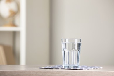 Glass of pure water on wooden table indoors. Space for text