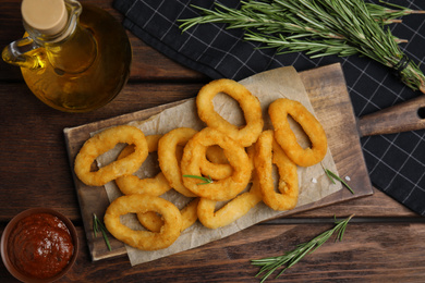 Fried onion rings served on wooden table, flat lay