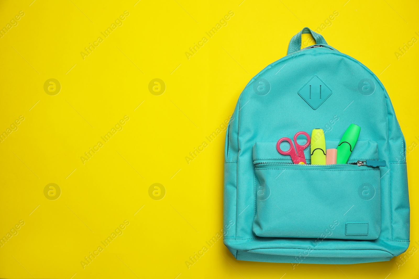 Photo of Stylish backpack with different school stationary on yellow background, top view. Space for text