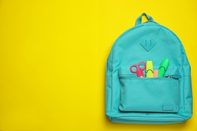 Photo of Stylish backpack with different school stationary on yellow background, top view. Space for text