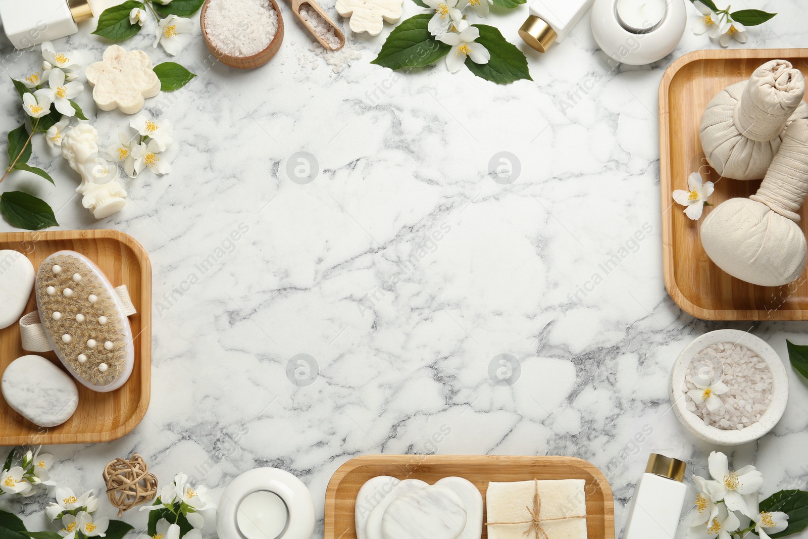 Photo of Jasmine flowers and set of spa essentials on white marble table, flat lay. Space for text