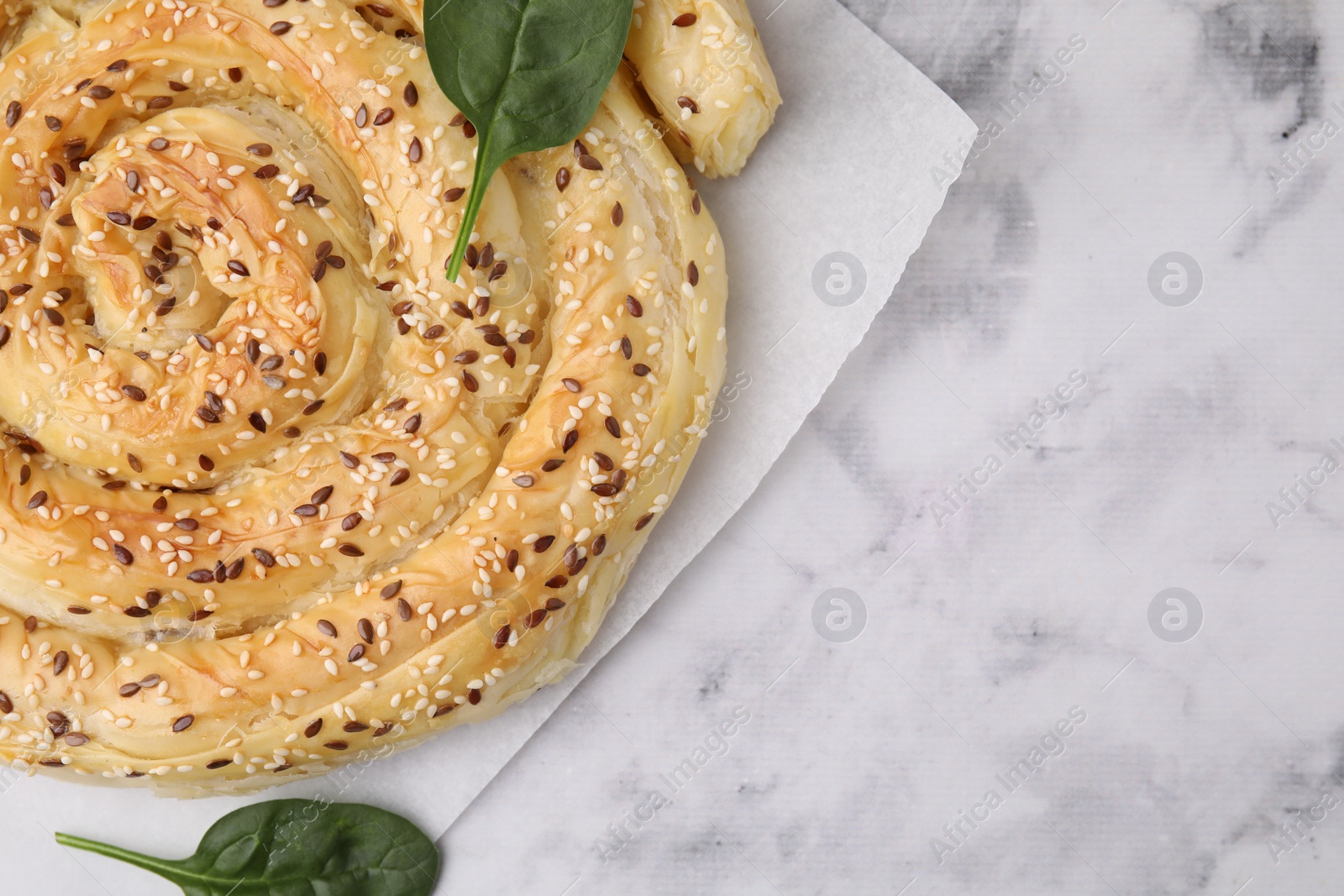 Photo of Delicious puff pastry with spinach on white marble table, top view. Space for text