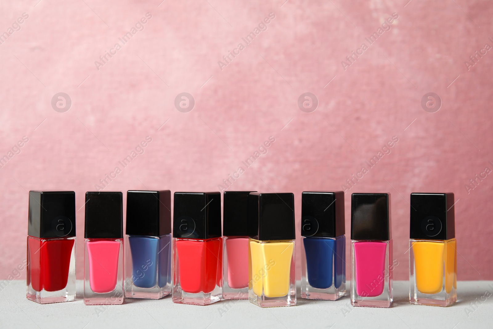 Photo of Bright nail polishes on table against color background. Space for text