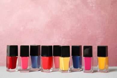 Photo of Bright nail polishes on table against color background. Space for text