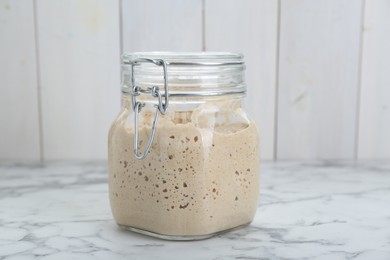 Leaven in glass jar on white marble table