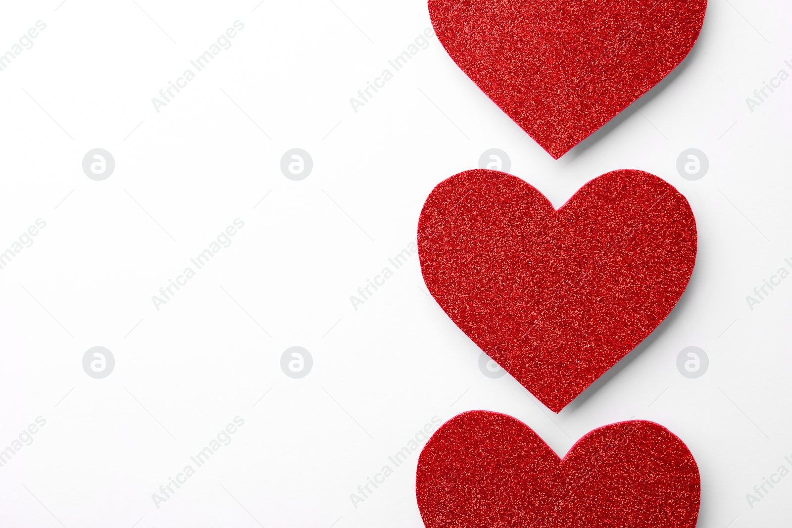 Photo of Red shiny paper hearts on white background, top view