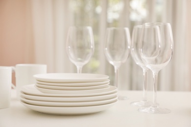 Photo of Stack of clean dishes, glasses and cups on table in kitchen