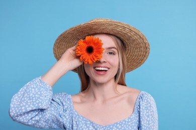 Photo of Beautiful woman with spring flower in hand on light blue background