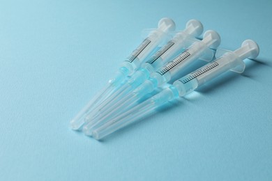 Photo of Disposable syringes with needles and medicine on light blue background