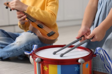 Photo of Little children playing toy musical instruments indoors, closeup