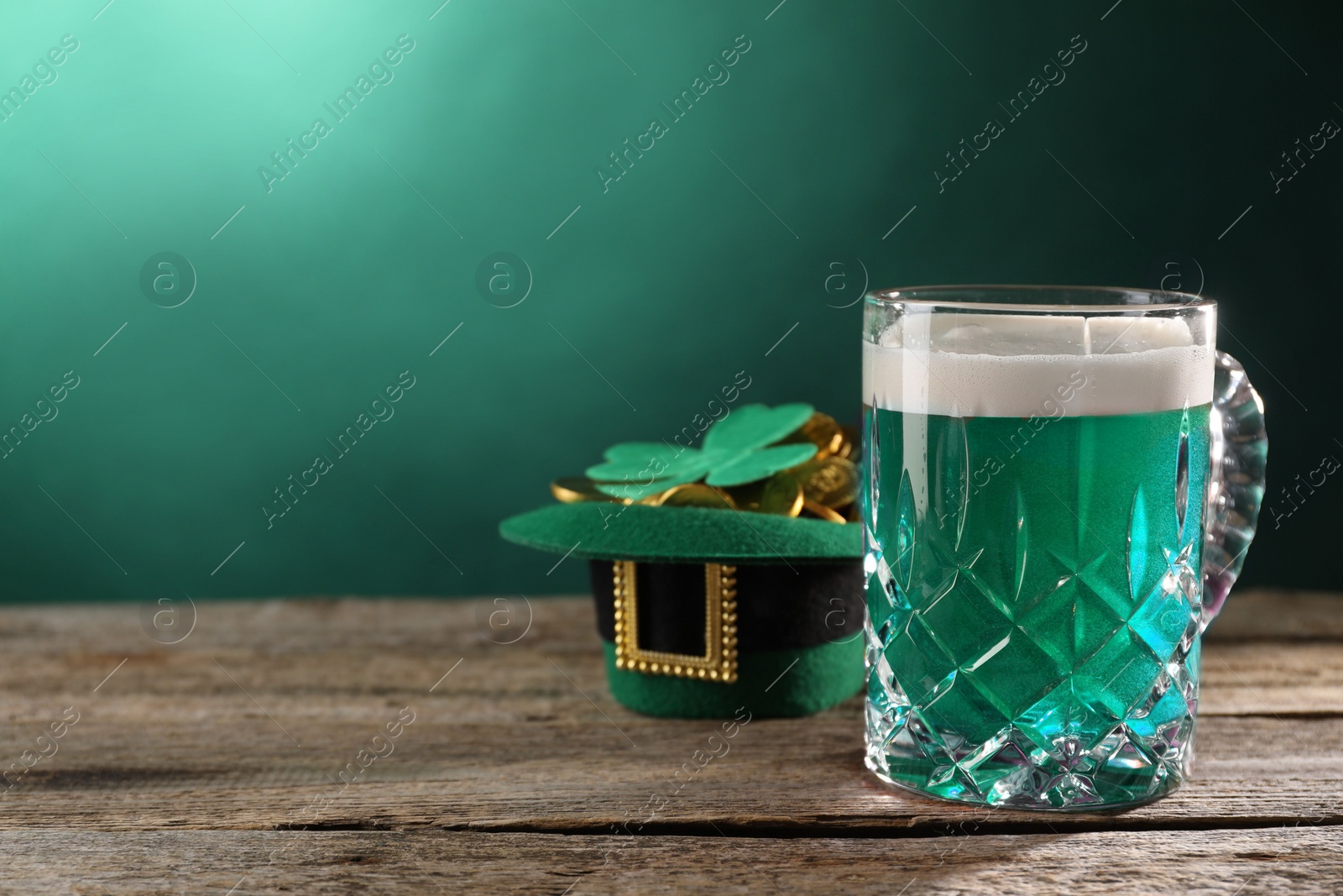 Photo of St. Patrick's day celebration. Green beer, leprechaun hat with gold and decorative clover leaf on wooden table. Space for text