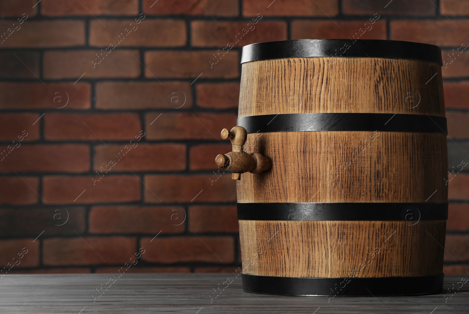 Photo of Wooden barrel with tap on table near brick wall, space for text