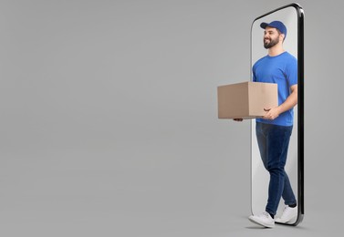 Courier with parcel walking out from huge smartphone on grey background. Delivery service. Space for text