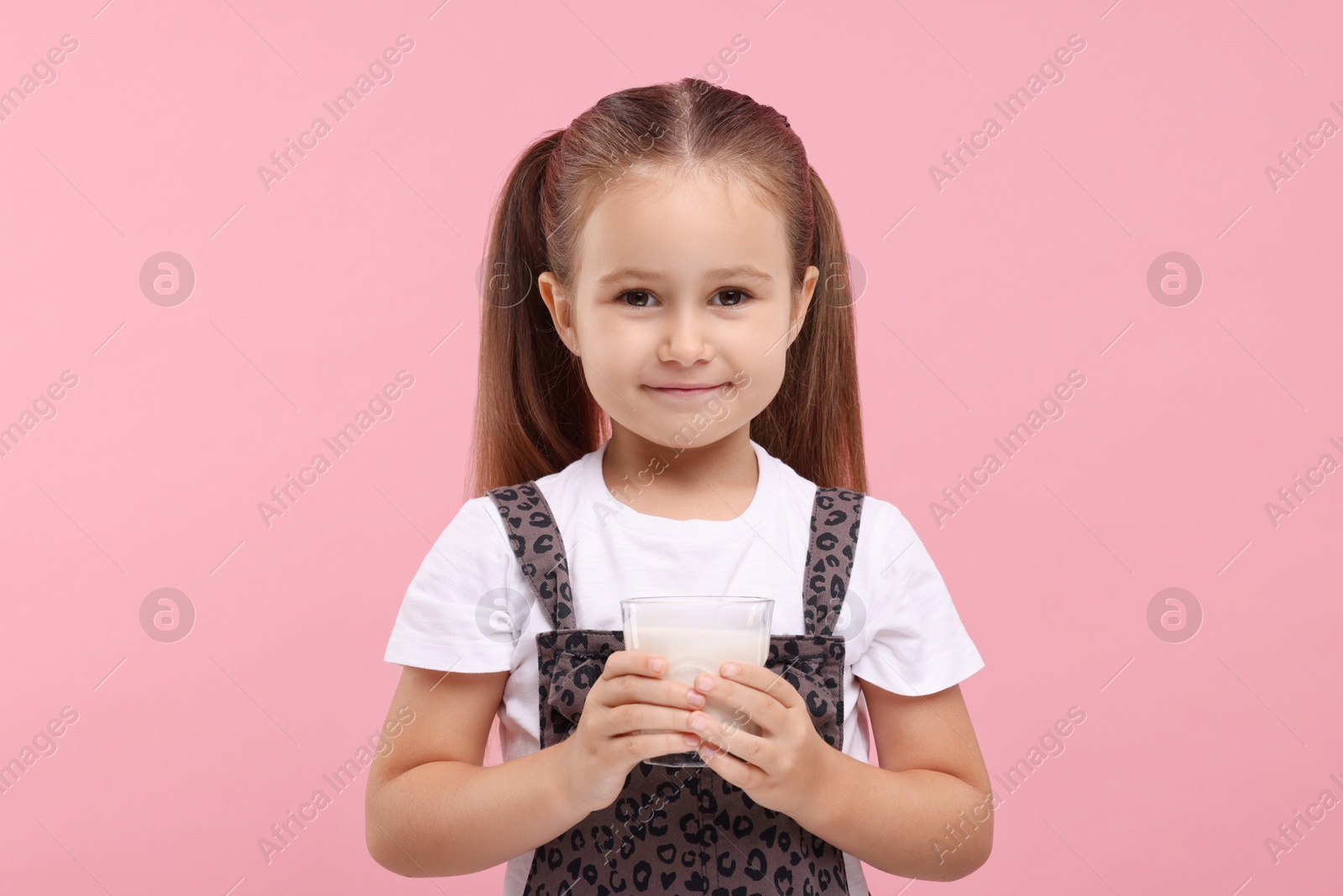 Photo of Cute girl with glass of fresh milk on pink background