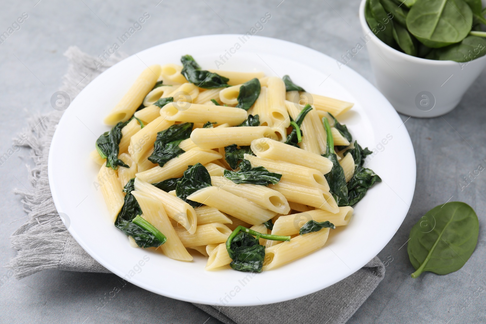 Photo of Tasty pasta with spinach and sauce on grey table