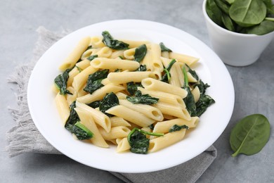 Photo of Tasty pasta with spinach and sauce on grey table