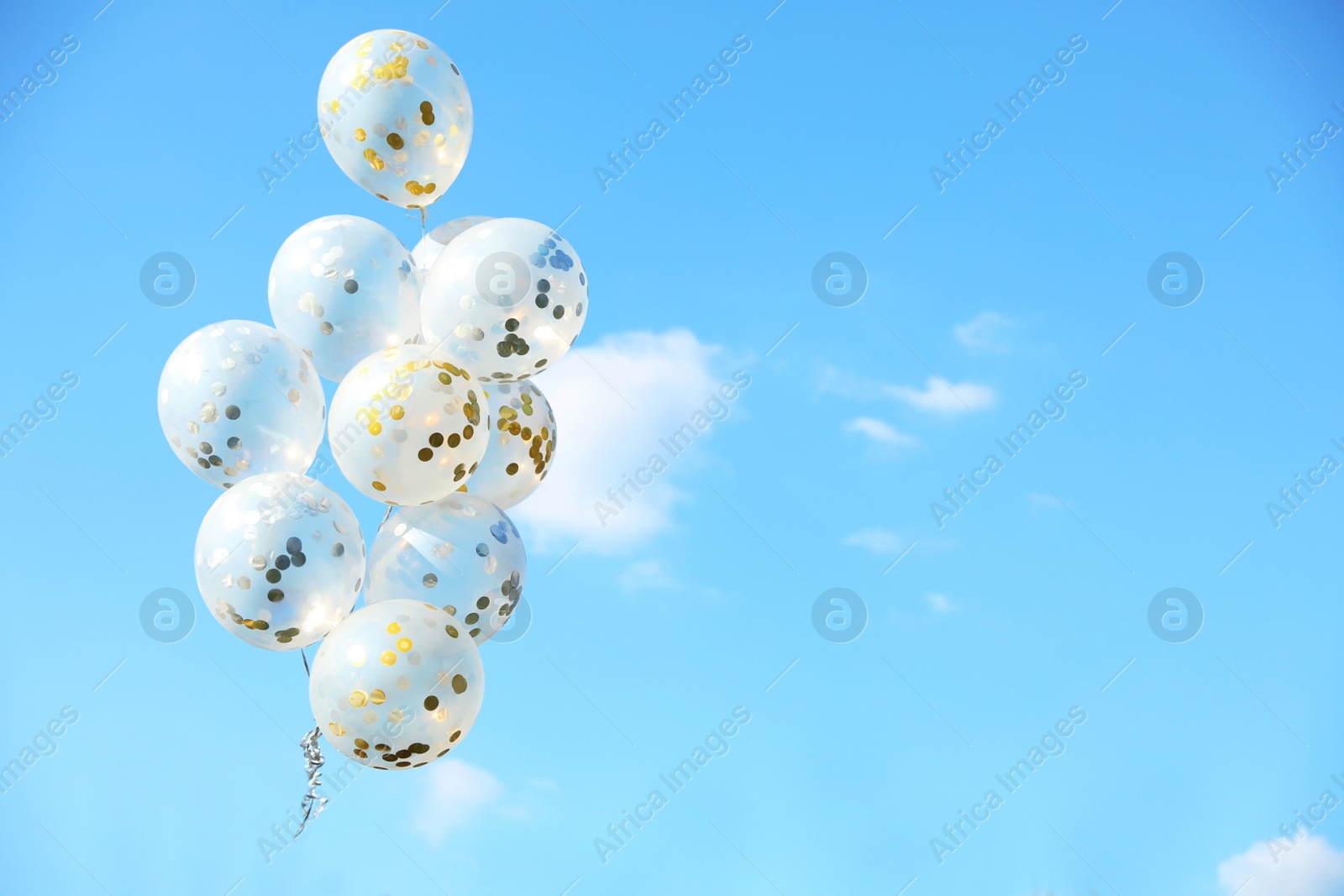 Photo of Glitter balloons against blue sky on sunny day outdoors. Space for text