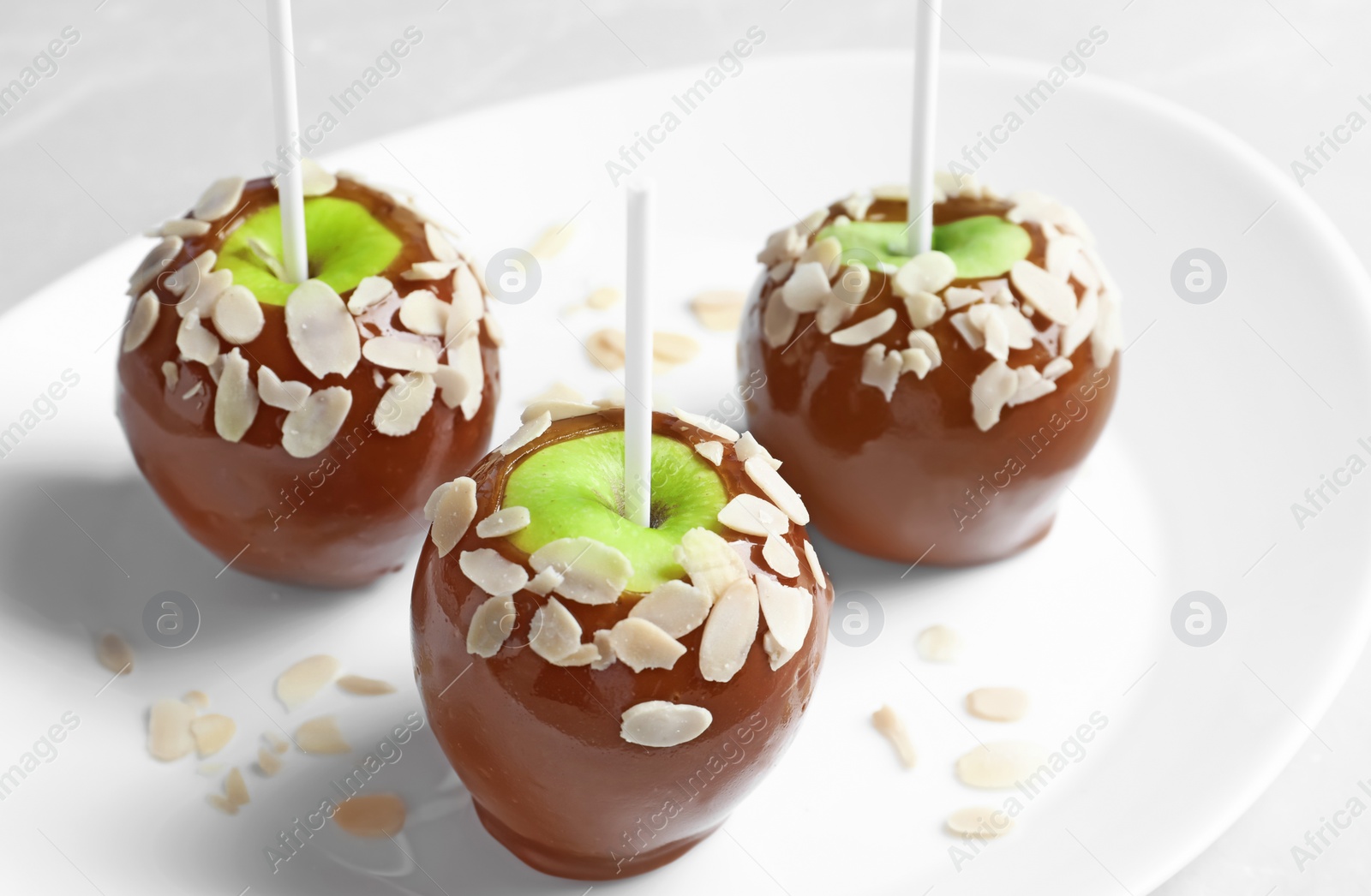 Photo of Plate with delicious caramel apples on light background