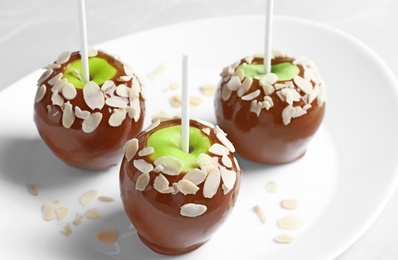 Plate with delicious caramel apples on light background