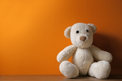 Photo of Abandoned teddy bear on table against color background. Time to visit child psychologist